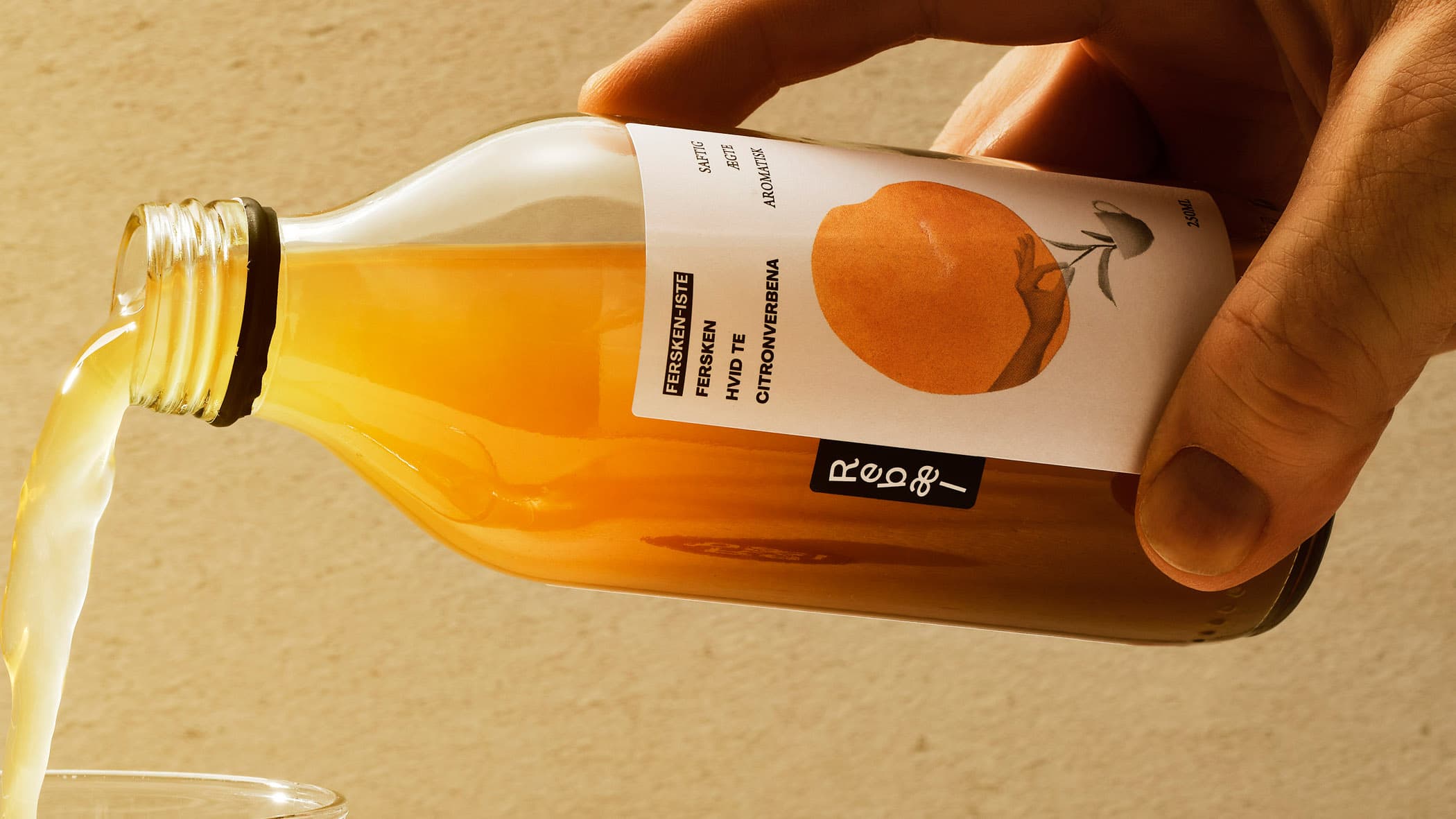 Close-up of hand pouring juice from a bottle of Rebel