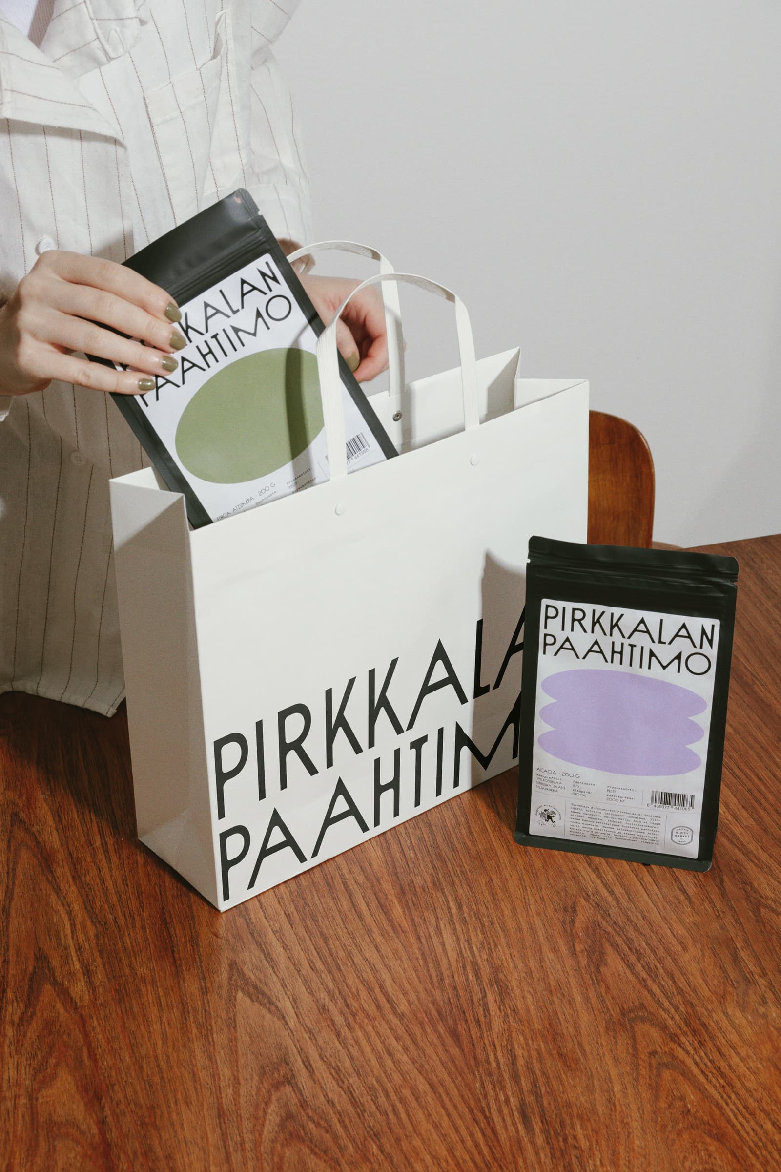 Woman putting small packs of coffee in a paper bag, all from Pirkkalan.