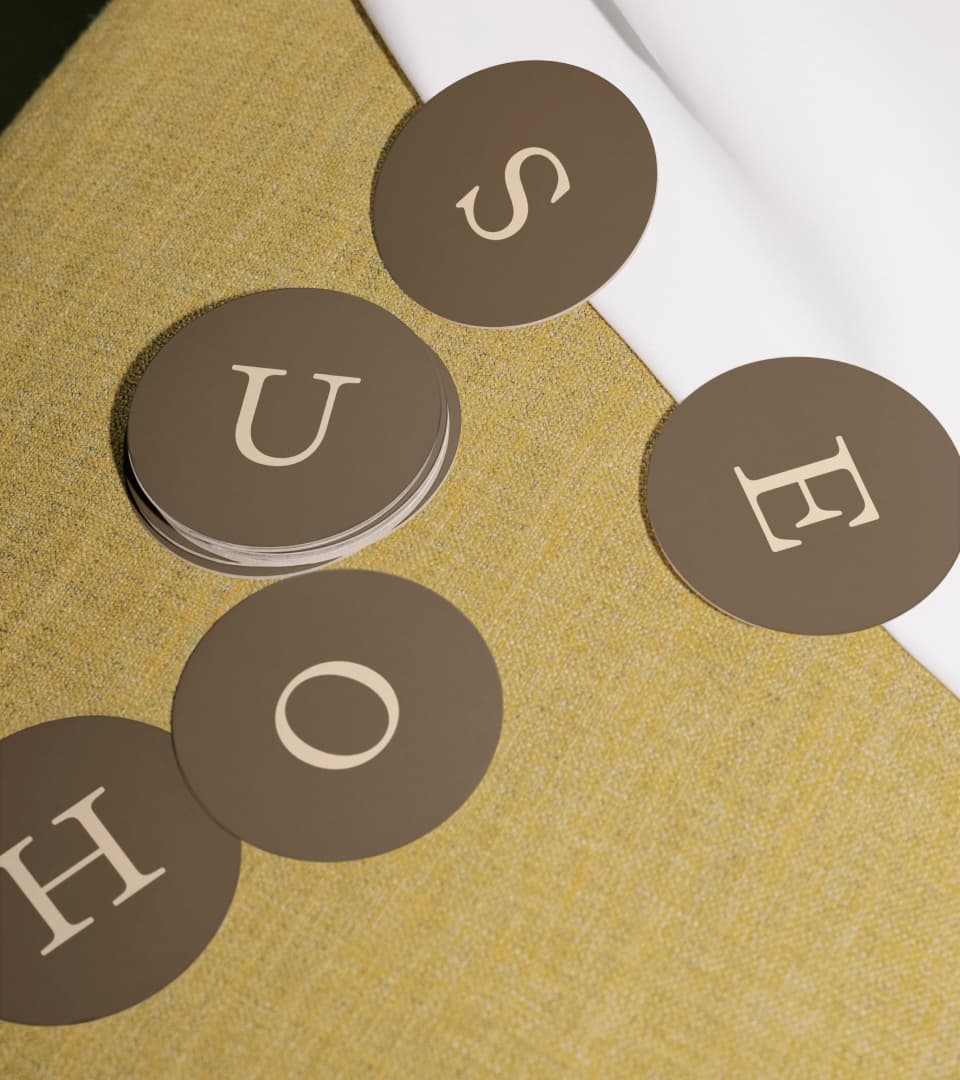 Scattered circular coasters spelling 'H O U S E'.