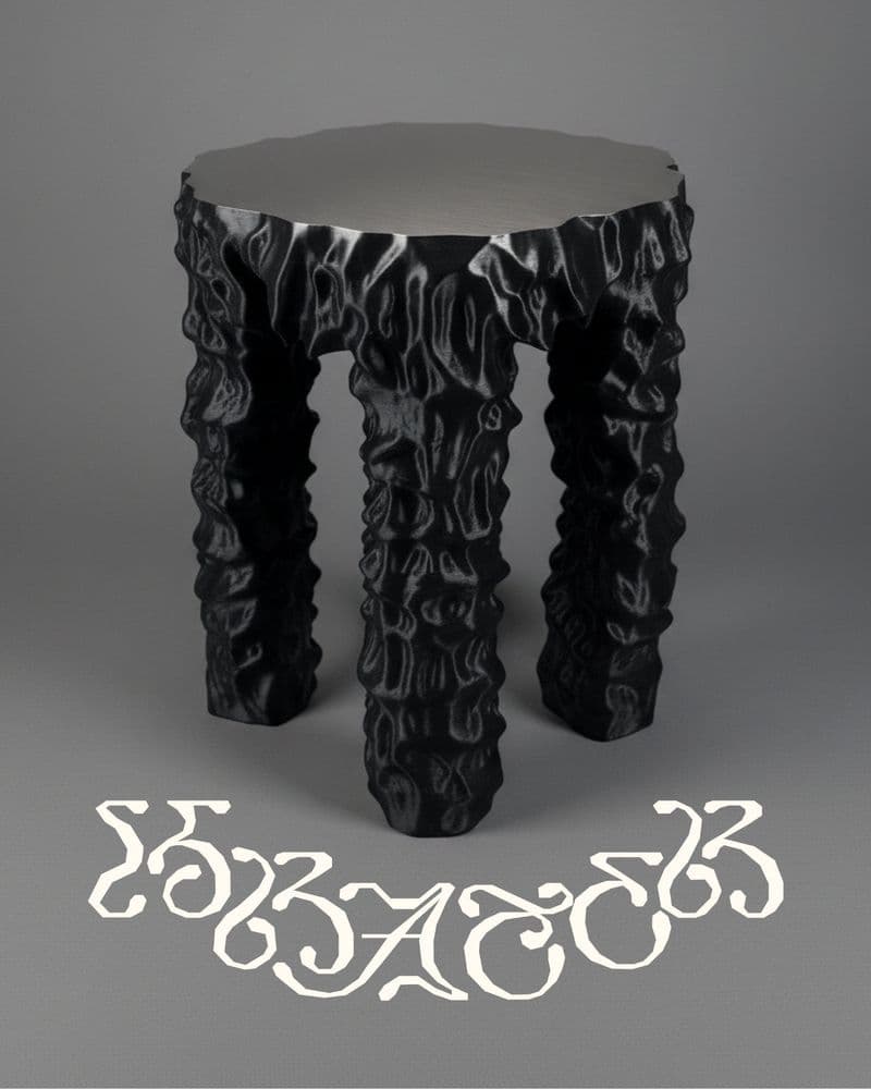 Krater.Objects wordmark logo above Table.01: a round side table with a brushed steel top and three deeply textured, rippled black legs, shot against a plain grey studio backdrop.