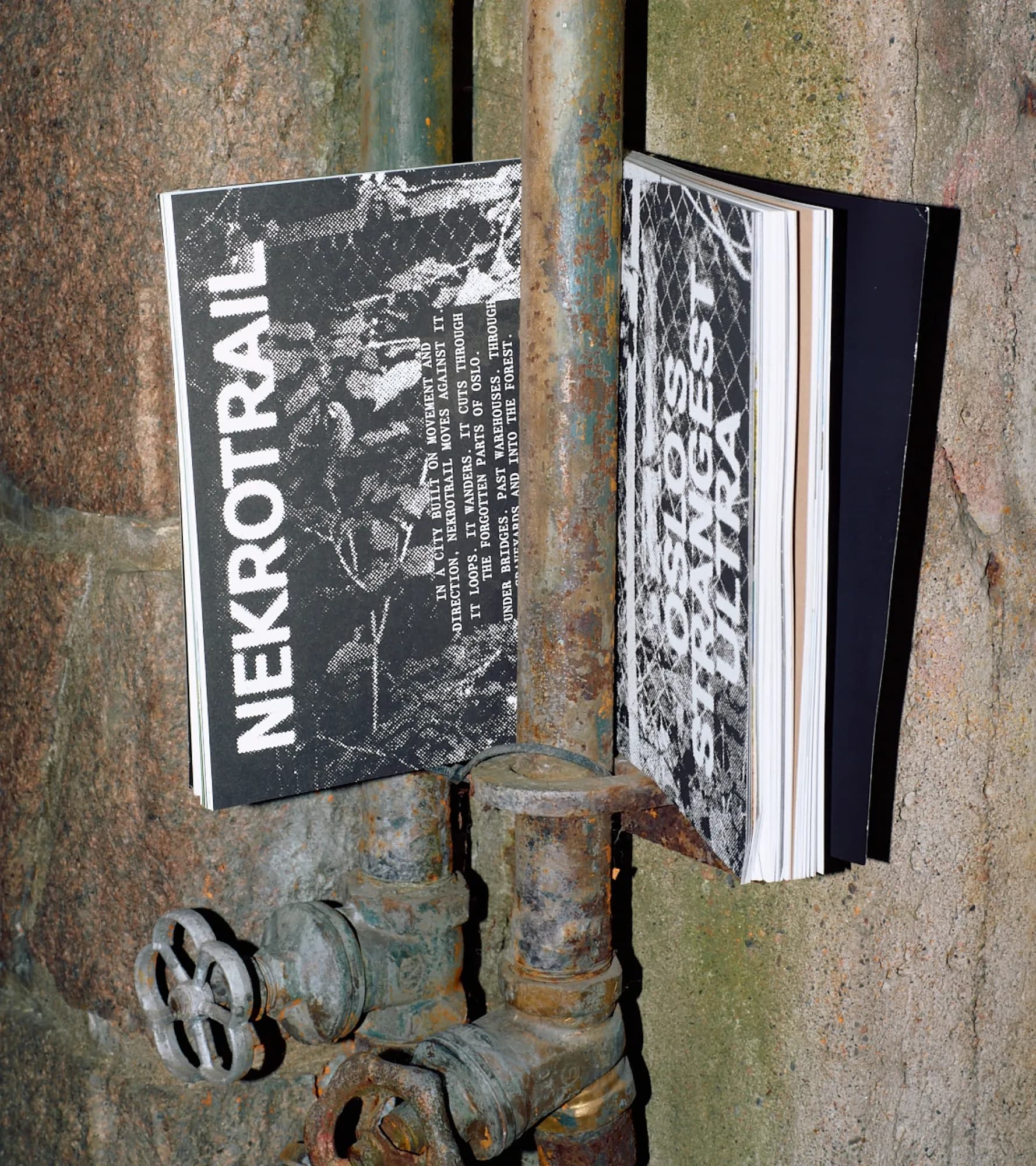 Two zine-style Kadens covers, 'Nekrotrail' and 'Oslo's Strangest Ultra', in raw black-and-white grunge typography, propped against rusty industrial pipes.