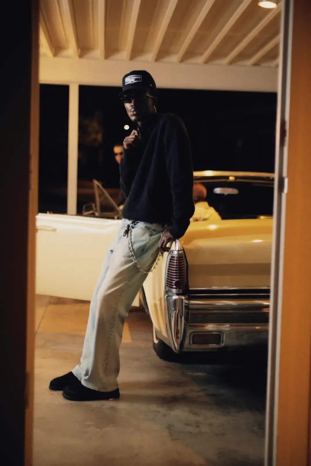 Guys wearing clothes bought at Represent, standing next to a yellow convertible parked in a garage.