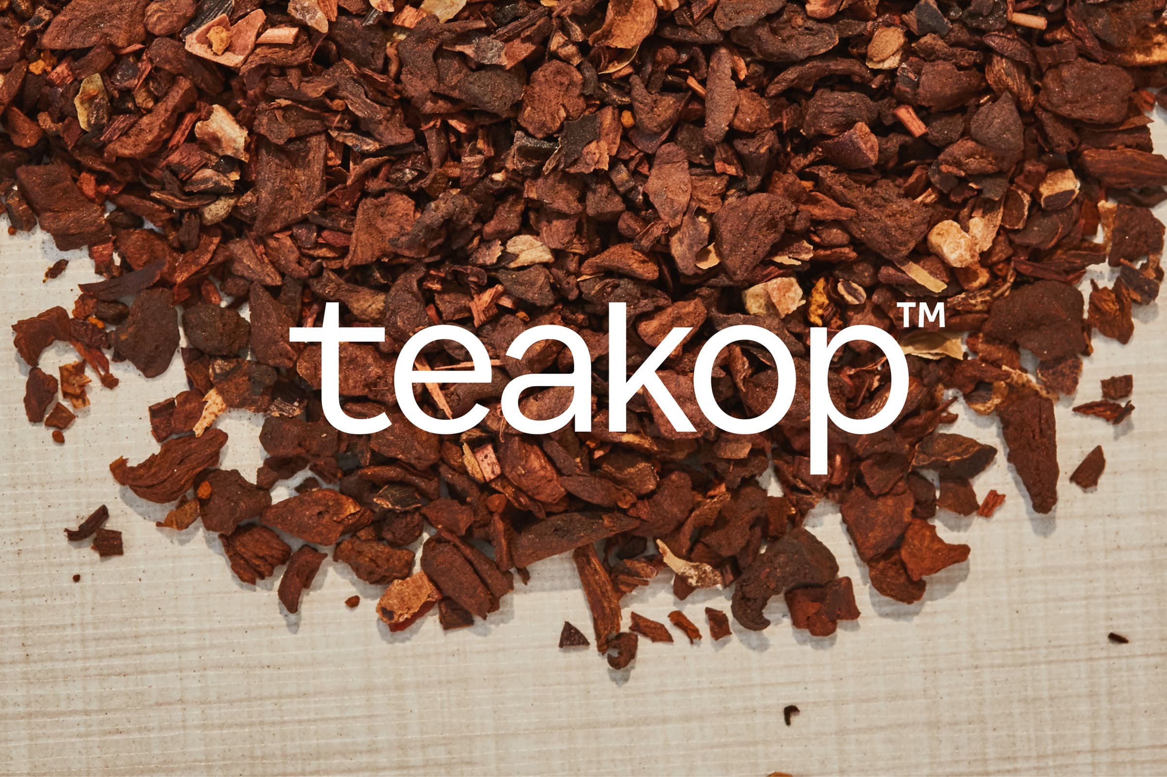 The teakop logo on a background a dried tea leaves