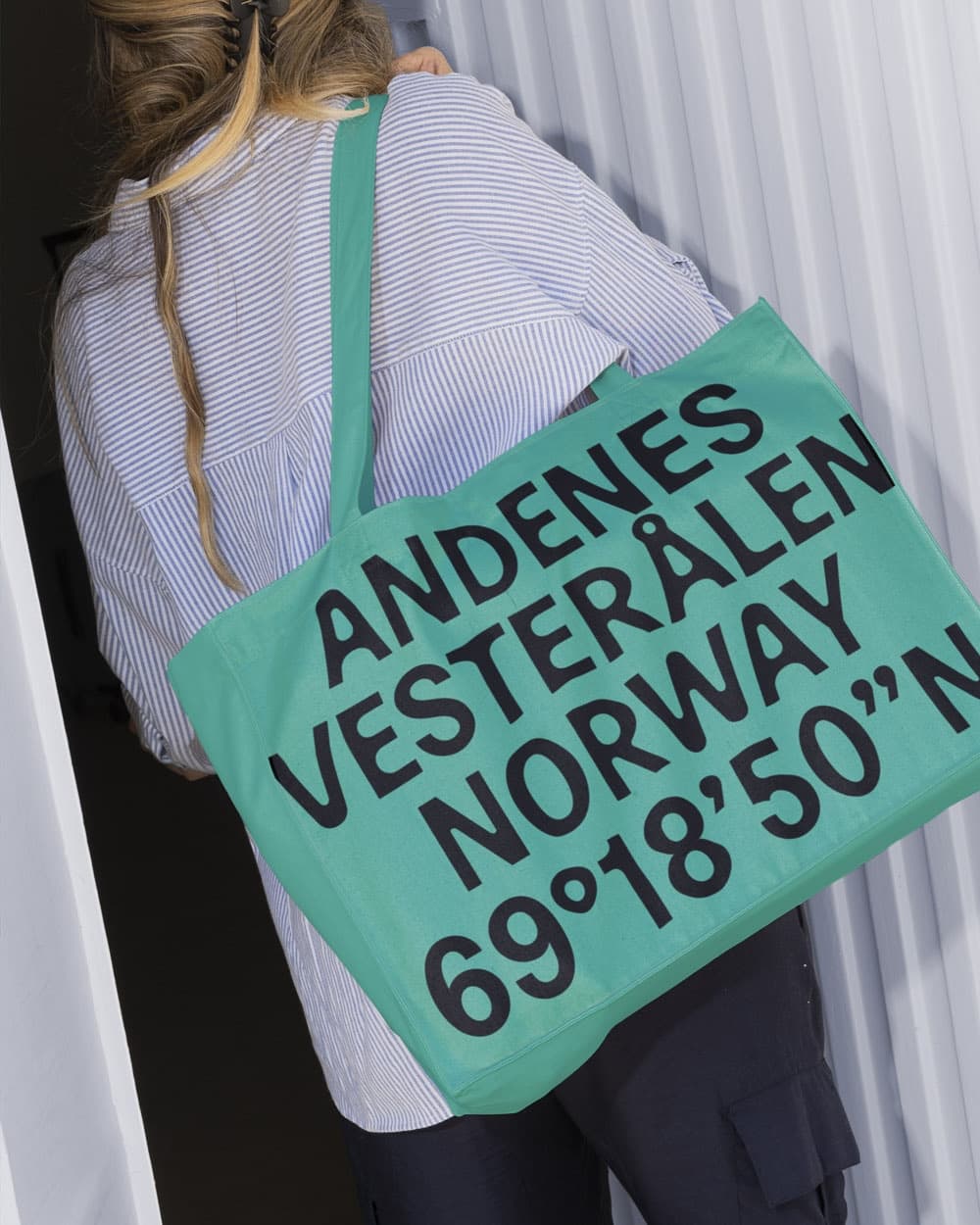 Woman carrying a turquoise tote bag printed with the location coordinates, part of new visual identity for The Whale