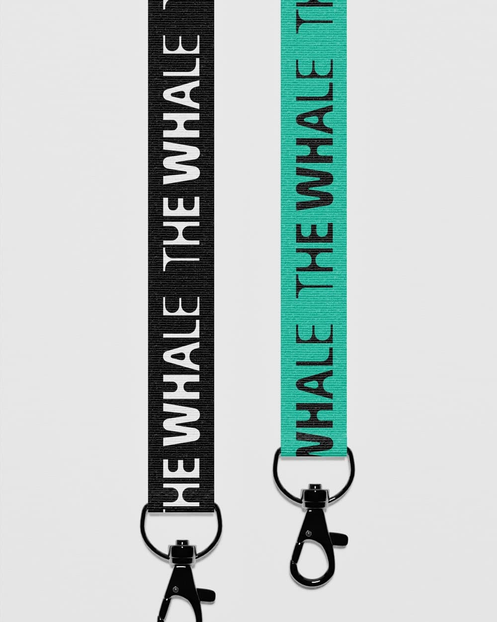 Two keyhangers – one black, one turquoise – both printed repeatedly with "The Whale" in contrasting colours.