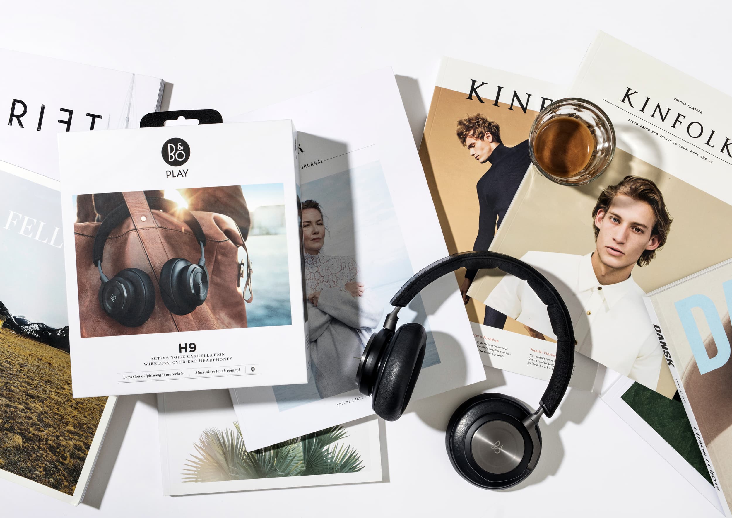 A pair of B&O Play Headphones H9 laying on a table next to its packaging