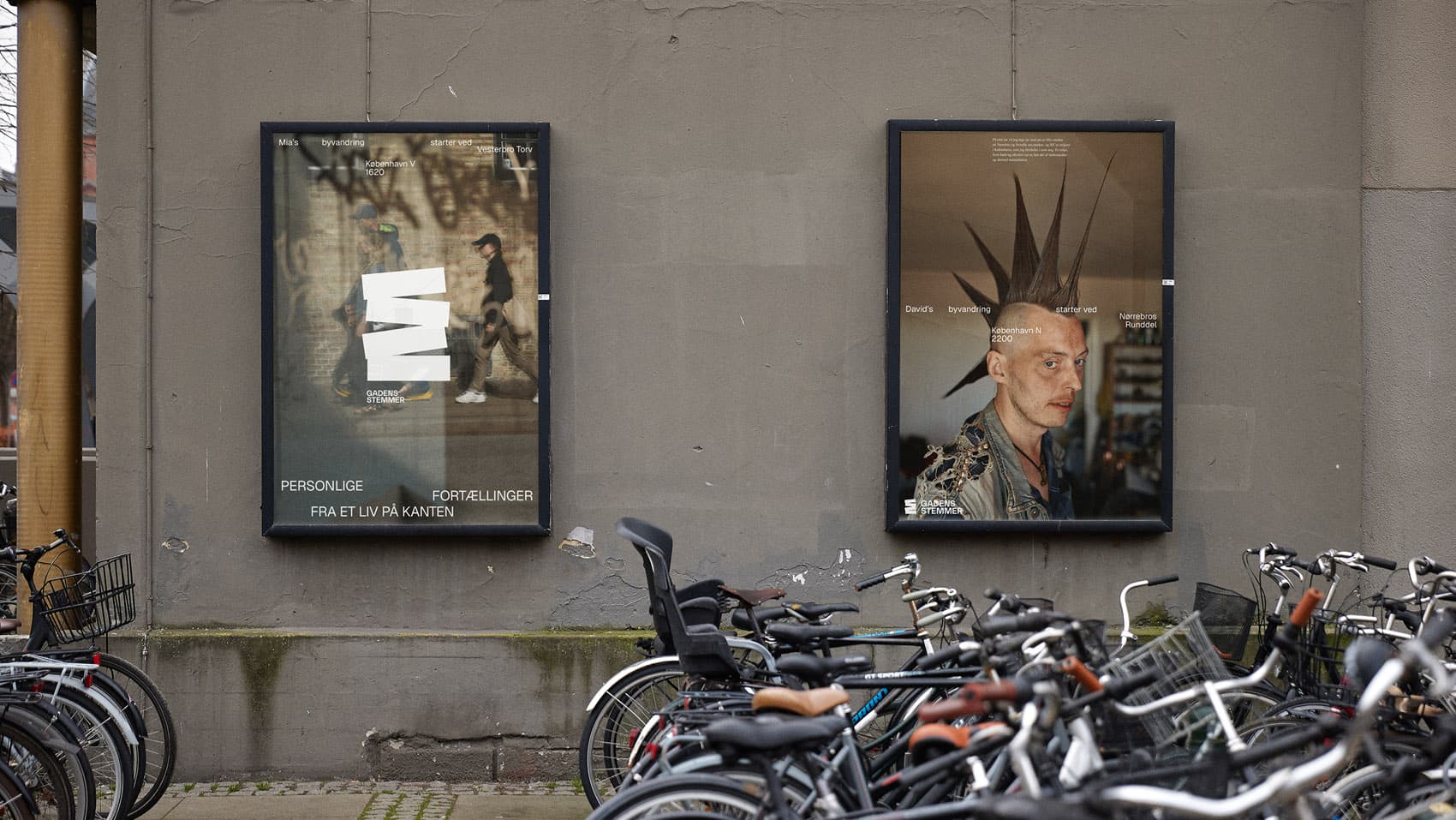 Two framed Gadens Stemmer campaign posters on a building facade above parked bicycles in an urban setting