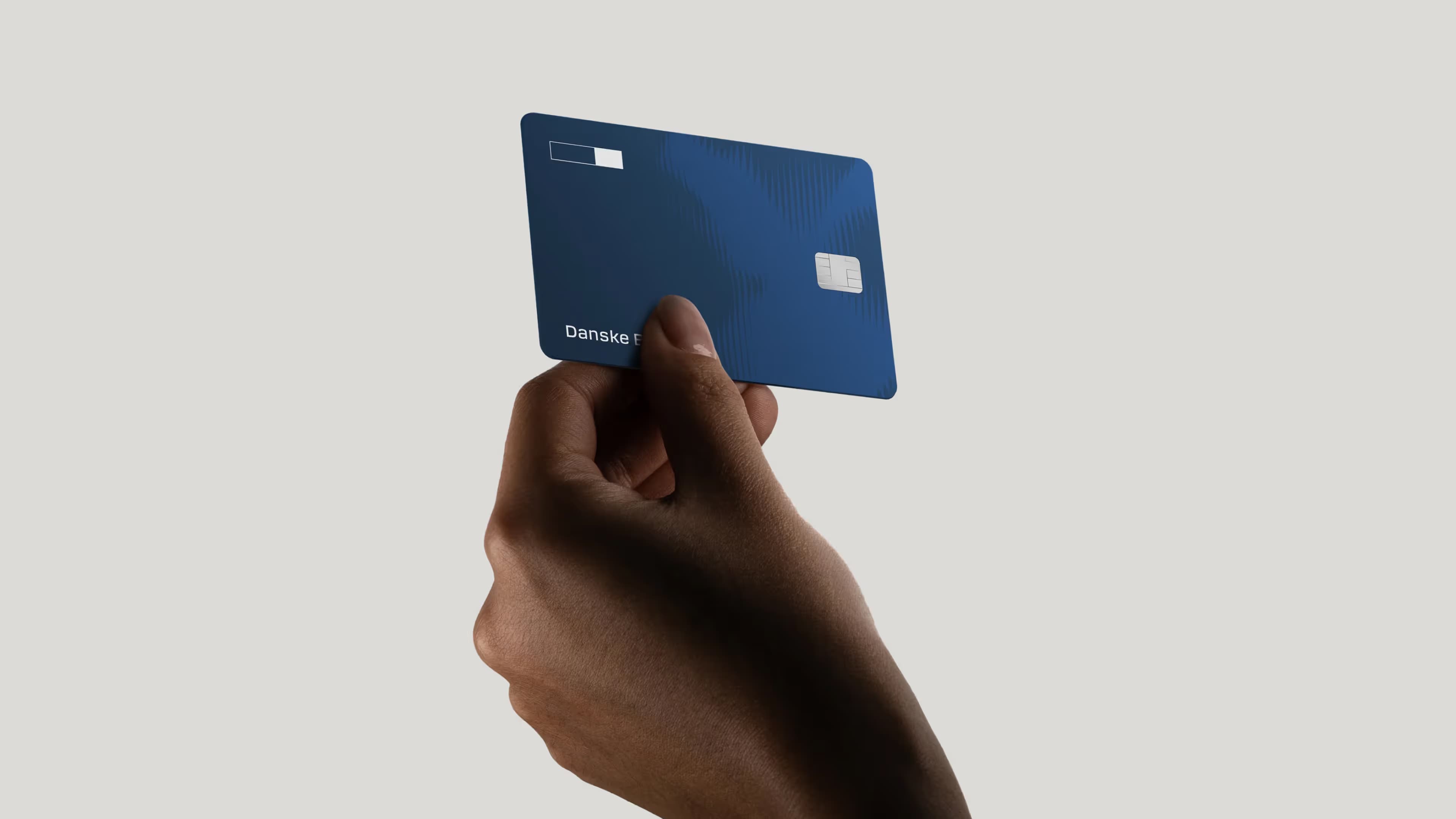 Hand holding a credit card from Danske Bank in the new visual identity